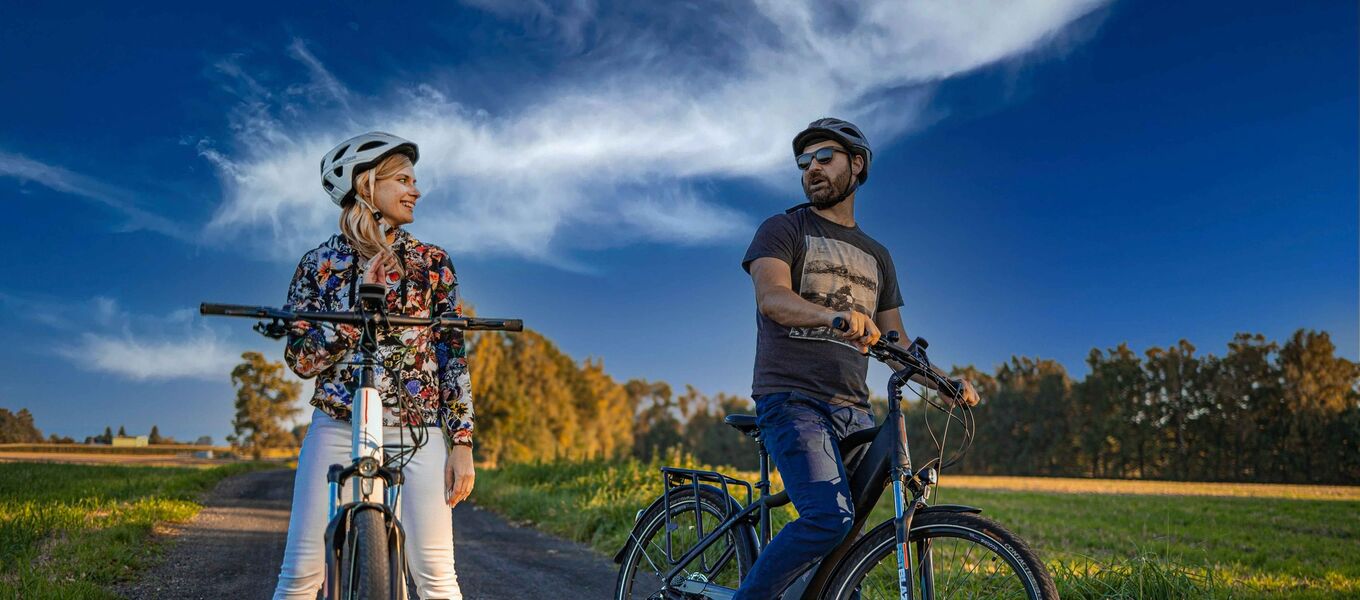 Dwie osoby z rowerami stojące na szlaku rowerowym