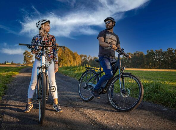 Dwie osoby z rowerami stojące na szlaku rowerowym